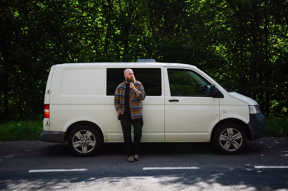 On-the-road colour portrait — host beside a white van