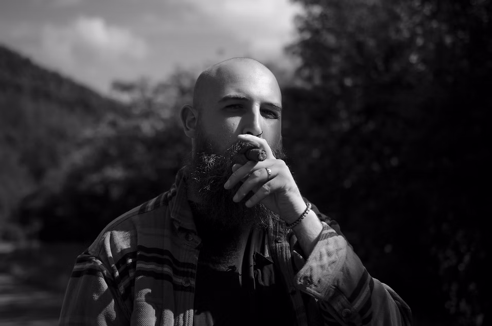 B&W documentary portrait — host smoking a cigar
