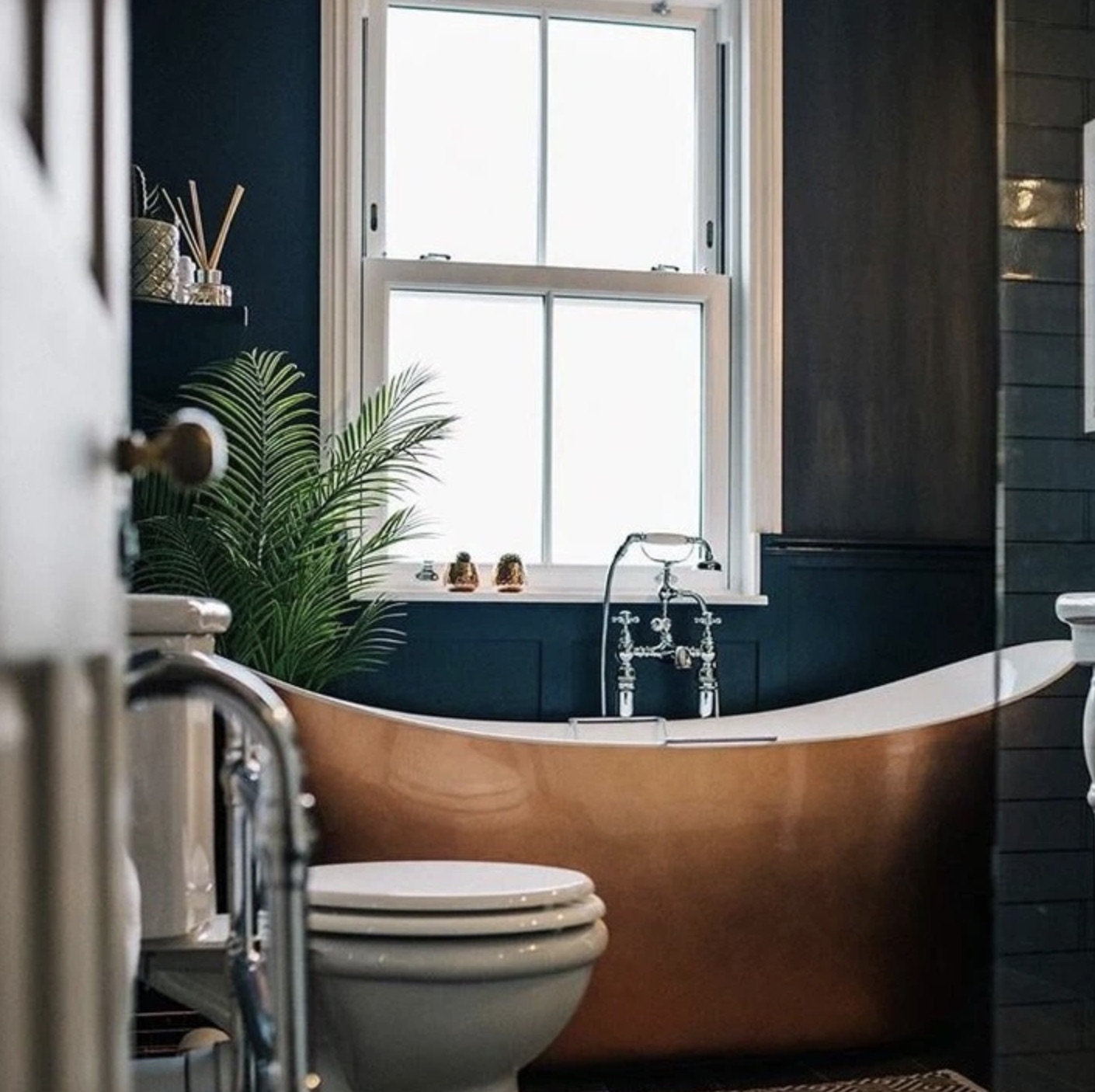 Renovated bathroom — copper bath, dark teal walls, brass fittings