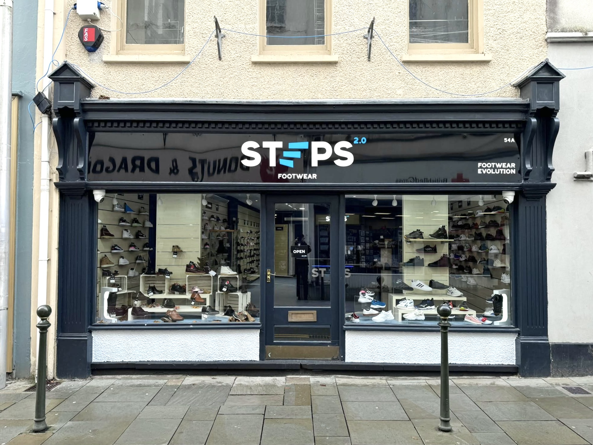 Steps 2.0 completed shopfront — black fascia, white wordmark, cyan slash marks, Swansea high street